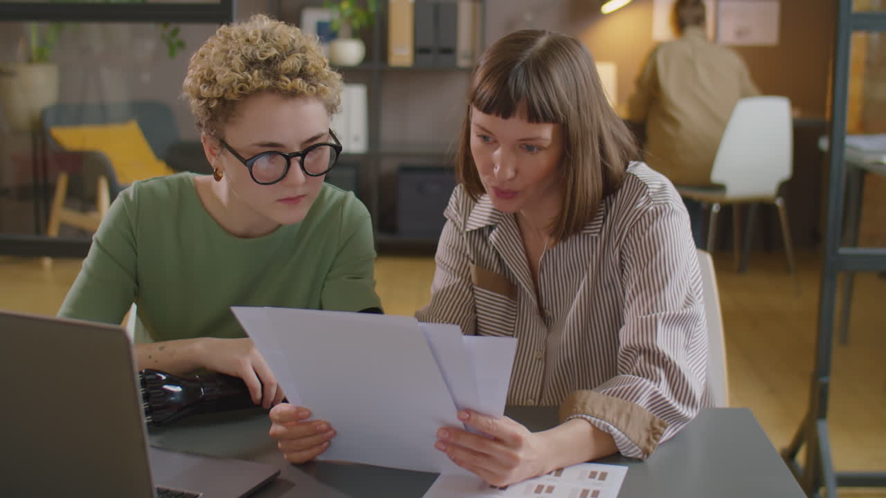 Woman with Prosthetic Arm Working on Business Project with Colleague
