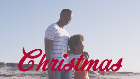 Animation-of-christmas-greetings-text-over-african-american-with-son-on-beach