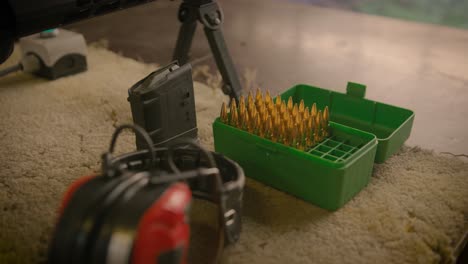 ammo box with shells, magazine and acoustic earmuffs at shooting range