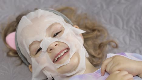 teen girl applying moisturizing face mask. child kid take care of skin with cosmetic facial mask