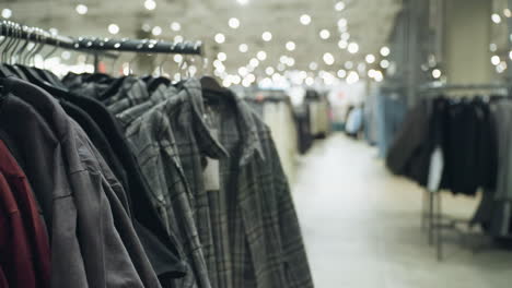 tienda de ropa que muestra una variedad de ropa en colgadores, incluidas camisas y chaquetas, con un fondo borroso. capturado con una cámara de mano, el video destaca la exhibición organizada