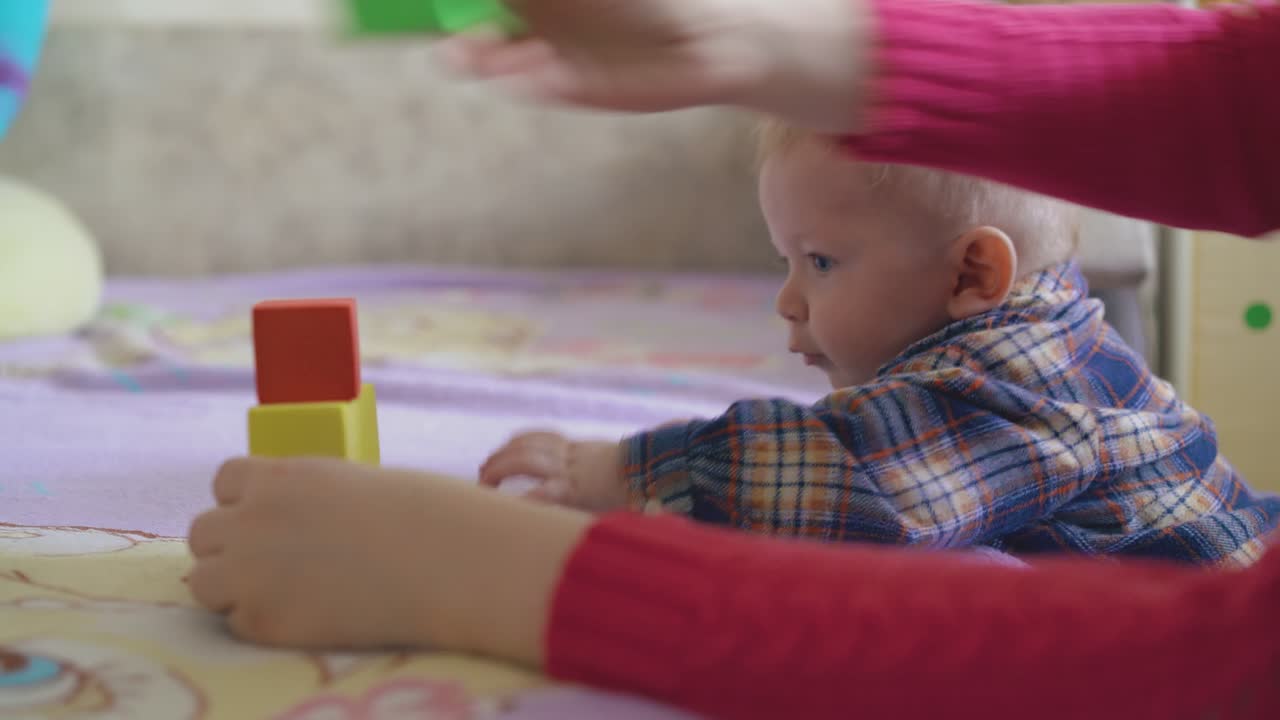 a mãe constrói uma torre com cubos de cores para um menino bonito interessado.