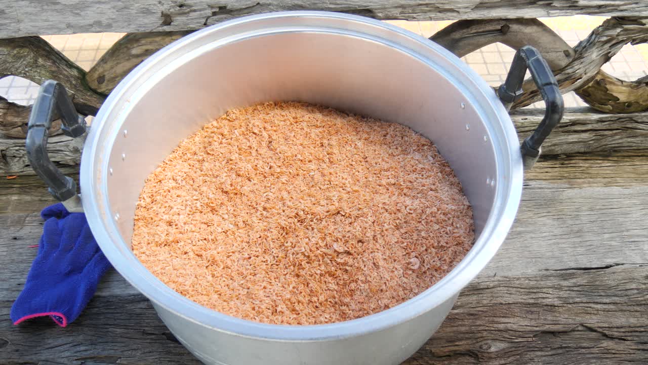 Large bowl filled with golden dried shrimp, used for cooking and street food in coastal areas of Thailand and Southeast Asia. Close-up detail showing texture and seasoning