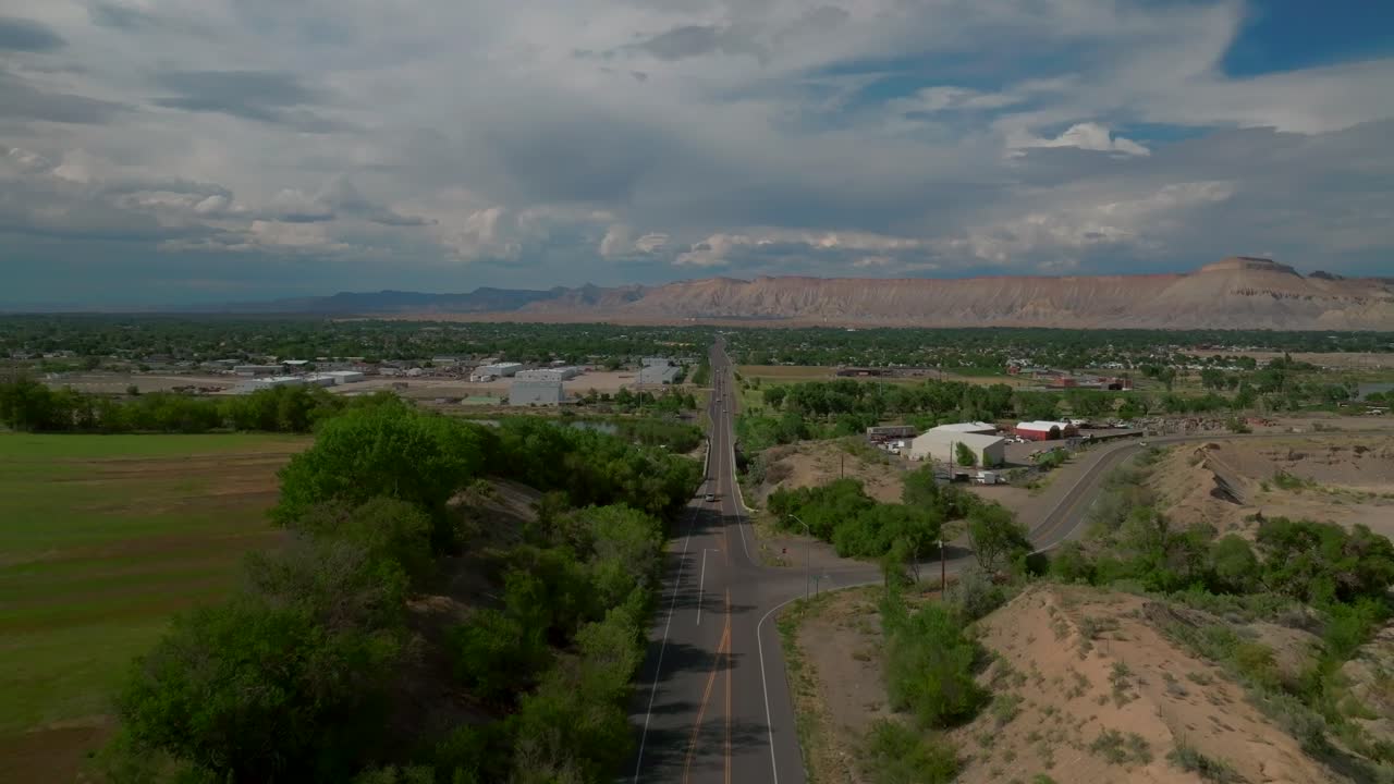 Grand Junction Colorado river aerial drone forward pan up Summer Grand Mesa downtown Main Street afternoon cloudy blue sky wine vineyards Parachute Fruitvale Mt Garfield Western slope cars traffic