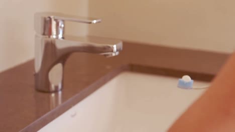 manos femeninas mojando el cepillo de dientes con pasta de dientes