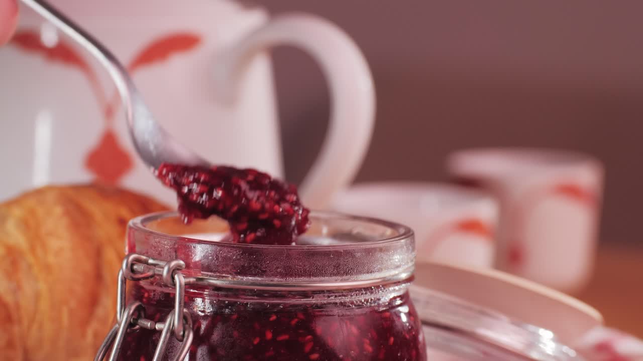 Spooning Raspberry Jam into a Jar During Breakfast