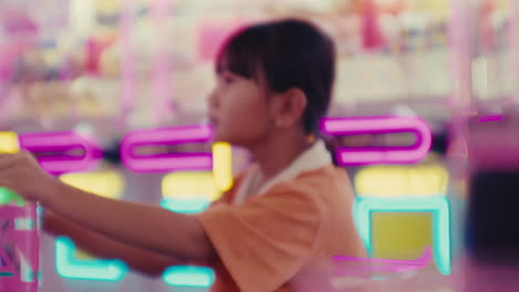 little adorable cute asiatic girl female kid playing video games in game room amusement park having fun during a funny holiday weekend day