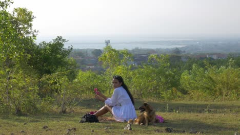 asian woman with white dress having a picnic with two small dogs