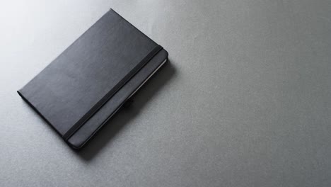 close up of closed gray notebook with copy space on gray background in slow motion