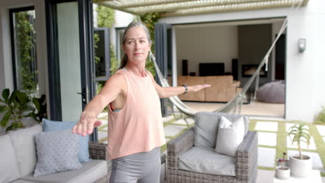 Mujer-Caucásica-Con-Pelo-Gris-Practicando-Yoga-En-Casa.