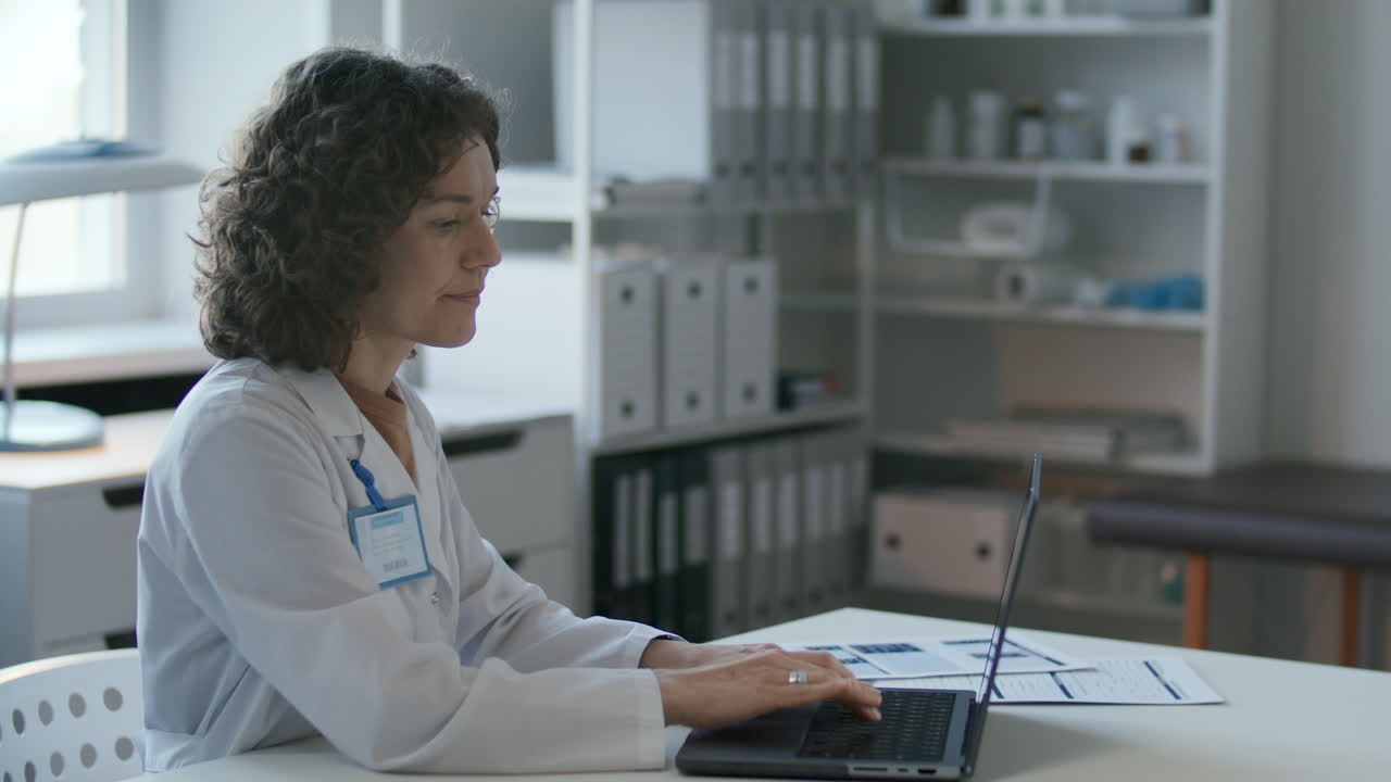 doctora trabajando en una computadora portátil en un escritorio en una oficina médica