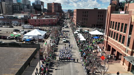 Vista-Aérea-De-Una-Banda-De-Marcha-Caminando-Por-Las-Calles-Del-Centro-De-Denver-En-Medio-De-La-Calle