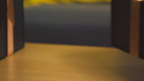 close up of man picking up gift wrapped present from table in lounge at home