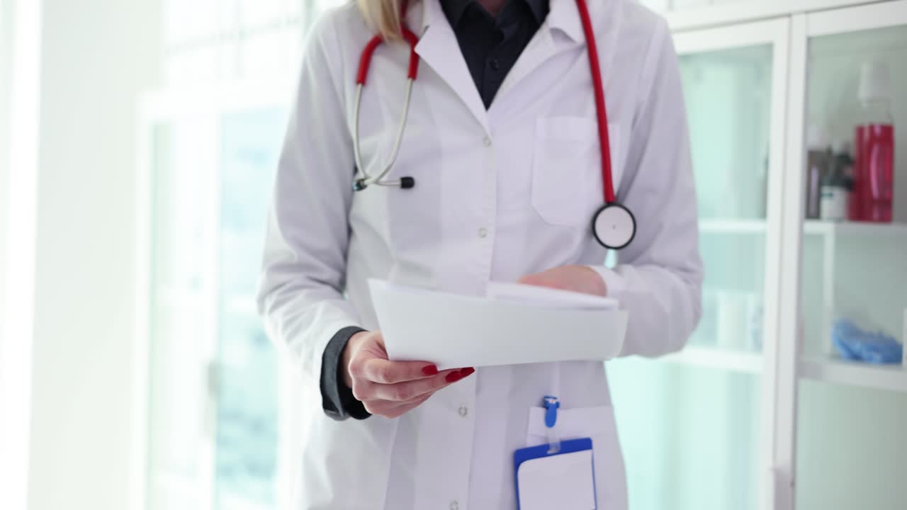 Doctor in White Coat with Stethoscope Holding Documents