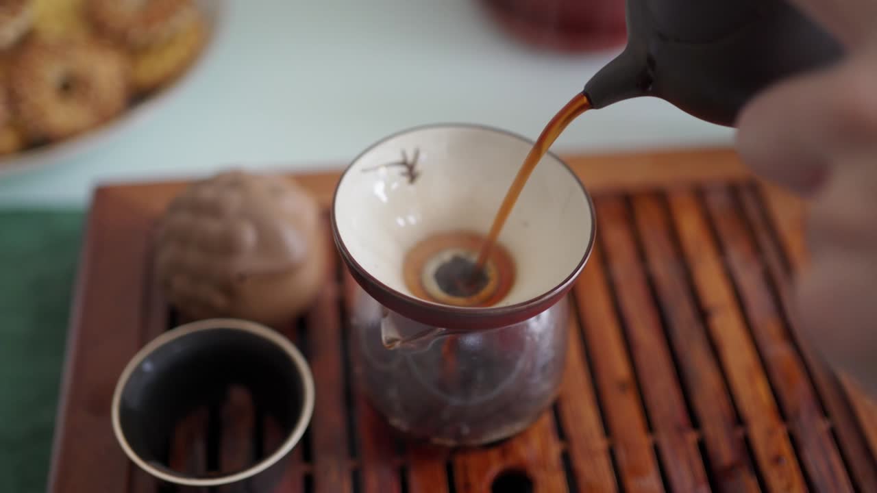 tea ceremony on a portable table. brewed tea is transferred through a funnel into an empty teapot, saturated with oxygen and revealing the taste of tea