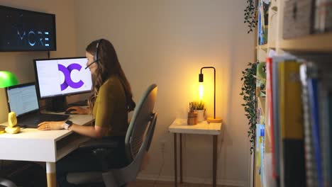 Sliding-reveal-shot-of-a-female-working-from-home-at-desk-on-the-computer-and-talking-on-the-phone-while-typing