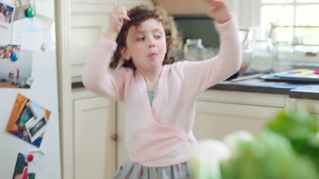Little Girl Playing with Toy Wand in Kitchen
