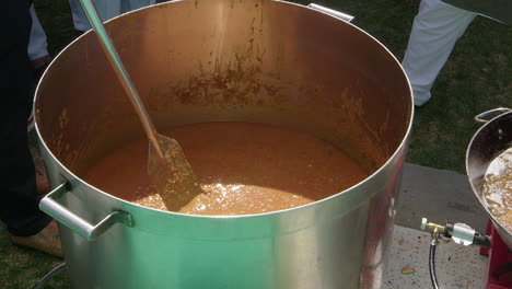 Lentil-dhal-in-huge-outdoor-vat-is-stirred-with-paddle,-Nagar-Kirtan