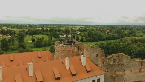 Toma-Aérea-Moviéndose-Hacia-Atrás-Desde-Las-Ruinas-Del-Castillo-De-Bauskas,-En-Letonia