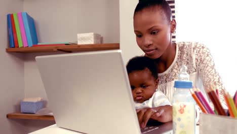 Smiling-mom-with-baby-typing-on-keyboard-