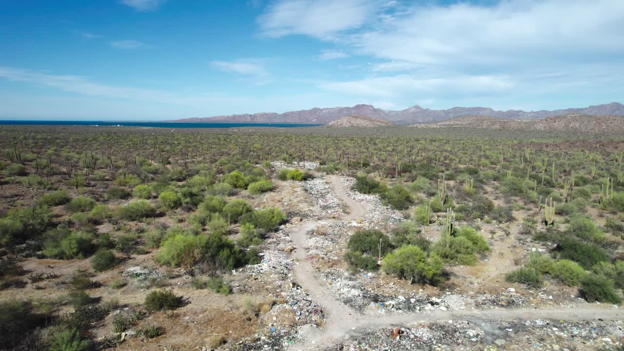 la basura que cubre la carretera menosprecia la belleza del paisaje desértico en mulege, baja california sur, méxico - avión no tripulado volando hacia adelante