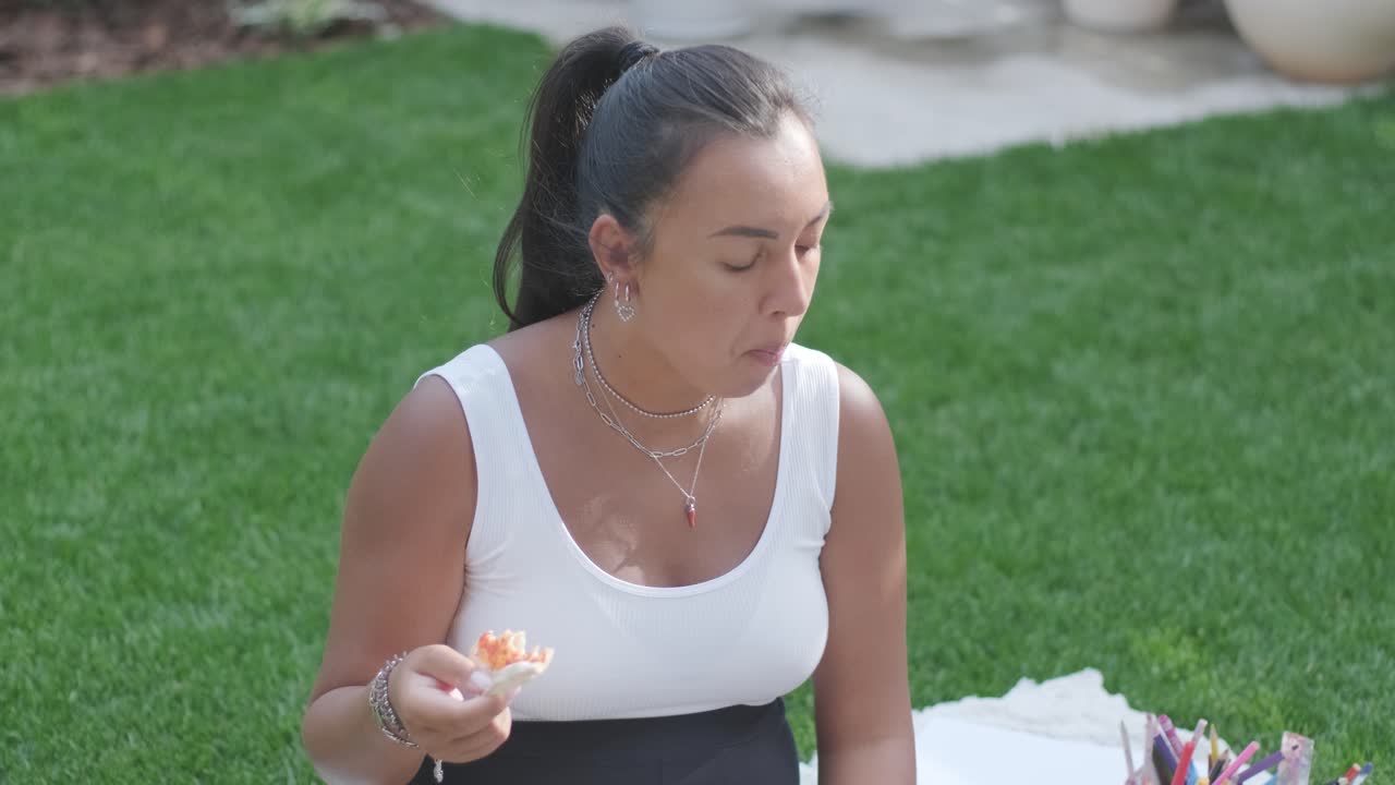 una madre y su hija pequeña se sientan en una manta en el patio trasero, participando en una actividad de dibujo juntos. la escena al aire libre captura un momento familiar pacífico, fomentando la creatividad y el vínculo.