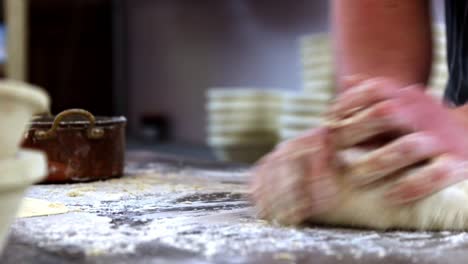 baker kneading bread dough roughly, close