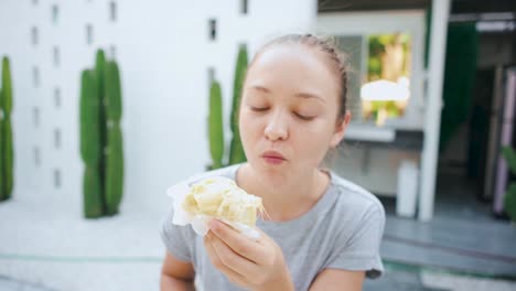mujer rubia comiendo sabroso durian al aire libre