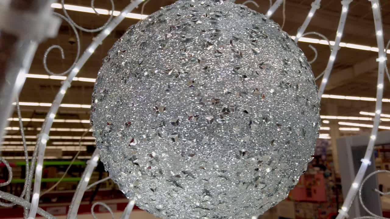 Close-up shot of sparkling silver Christmas ornament rotating inside shopping mall