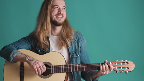 caucasian young man playing guitar and laughing on camera.