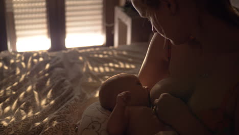 madre amamantando al bebé en el dormitorio