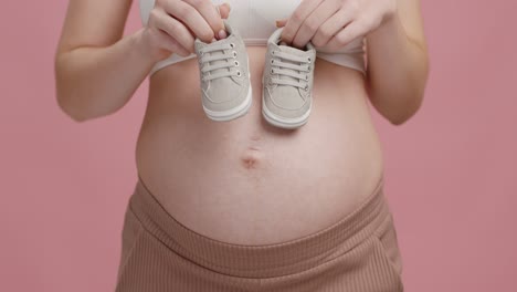 pregnant woman holding baby shoes