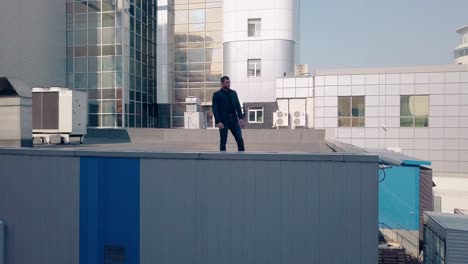 low angle shot handsome man in black suit on factory roof