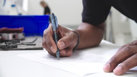 engineer making notes on technical drawing in factory