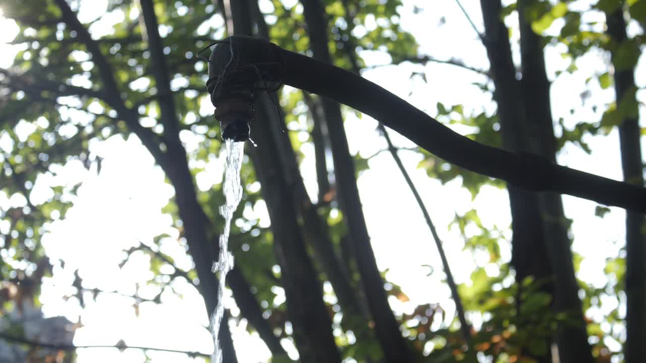 Fountain surrounded by nature, with flowing pure water in slow motion; slow motion video.