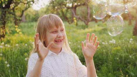 carefree girl is catching soap bubbles cheerfully a walk in the spring garden slow motion video