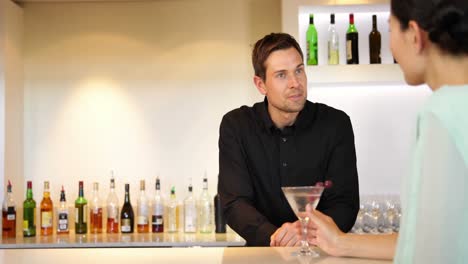 bartender serving a cocktail and chatting to customer