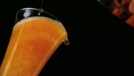 cerveza vertiendo en un vaso sobre un fondo negro vista de bajo ángulo
