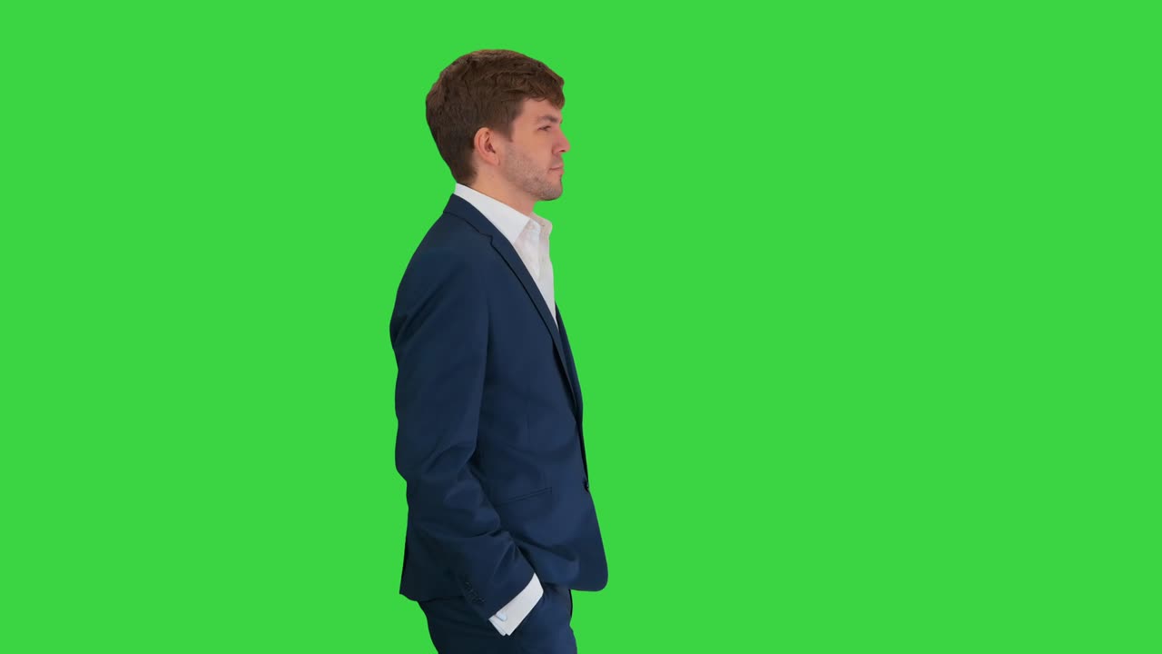 Giovane uomo d'affari sicuro di sé che cammina con le mani in tasca su uno schermo verde, Chroma Key
