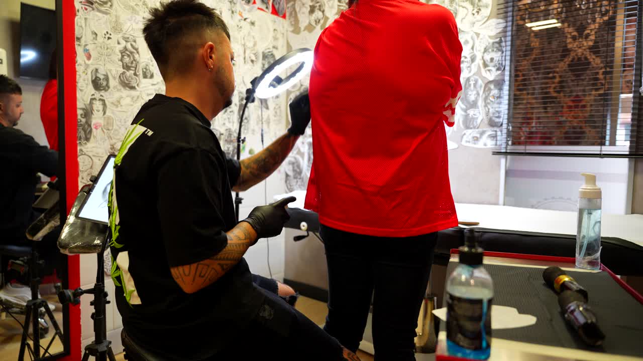 Artist prepares tools and cleans the client's arm, tattoo studio. Pan right