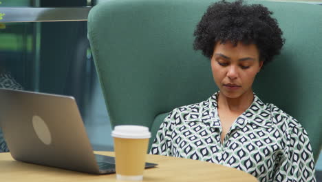 Mujer-De-Negocios-En-La-Mesa-En-La-Zona-De-Descanso-Del-Edificio-De-Oficinas-Despertándose-Después-De-Quedarse-Dormido