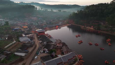 aerial drone tracking left of ban rak thai village, thailand, nestled among tranquil lake and mist covered mountains around homes