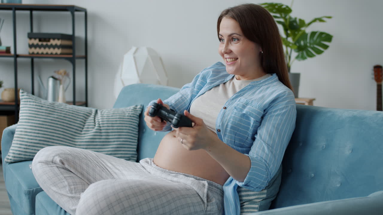 Pregnant woman playing video games at home