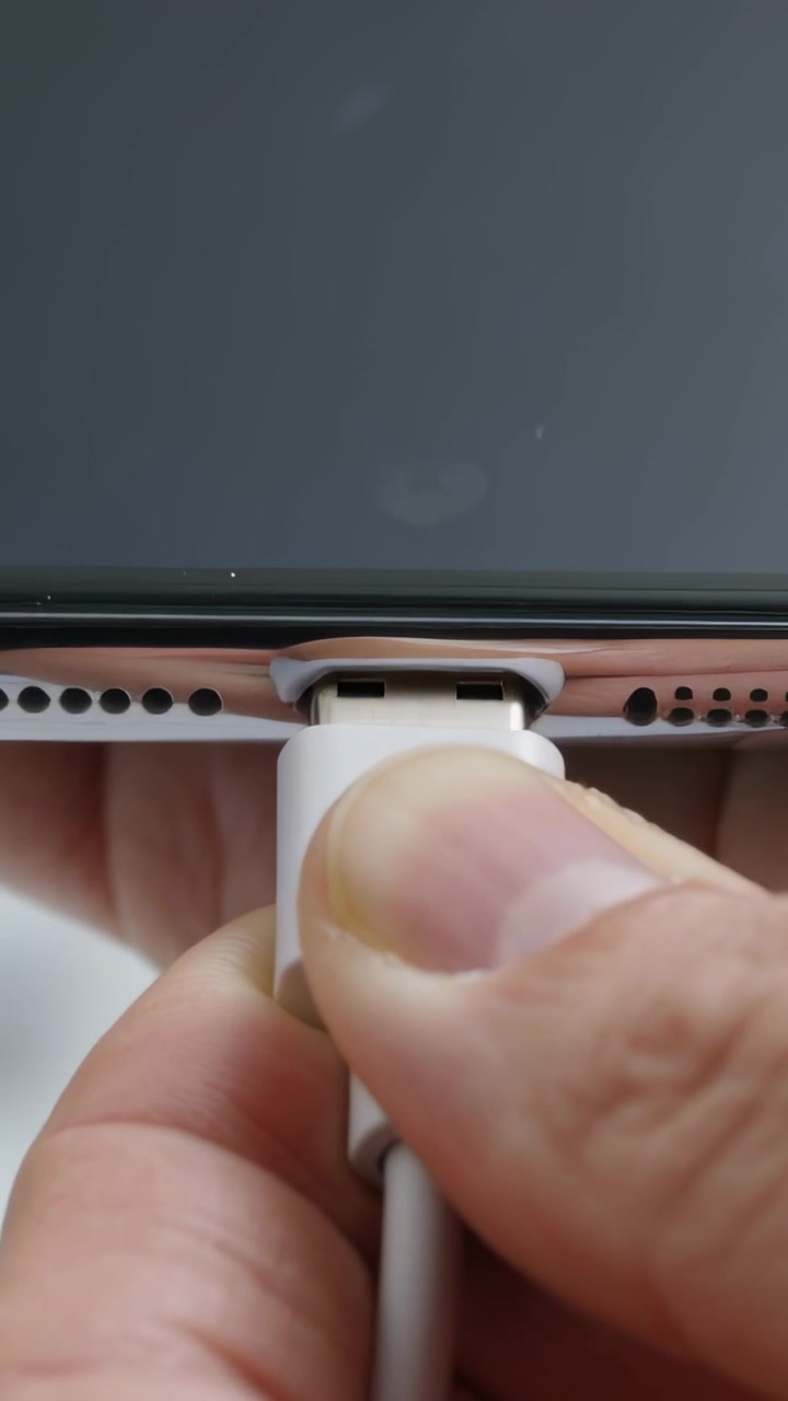 Vertical video: Pressing thumb sliding magnetic adapter from phone bottom edge, exposing metal plug