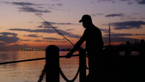 Rötliche-Silhouette-Des-Mannes,-Der-In-Der-Luft-Fischt