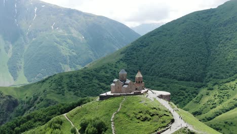 antiga igreja da trindade gergeti na majestosa paisagem montanhosa, visão de órbita aérea à distância