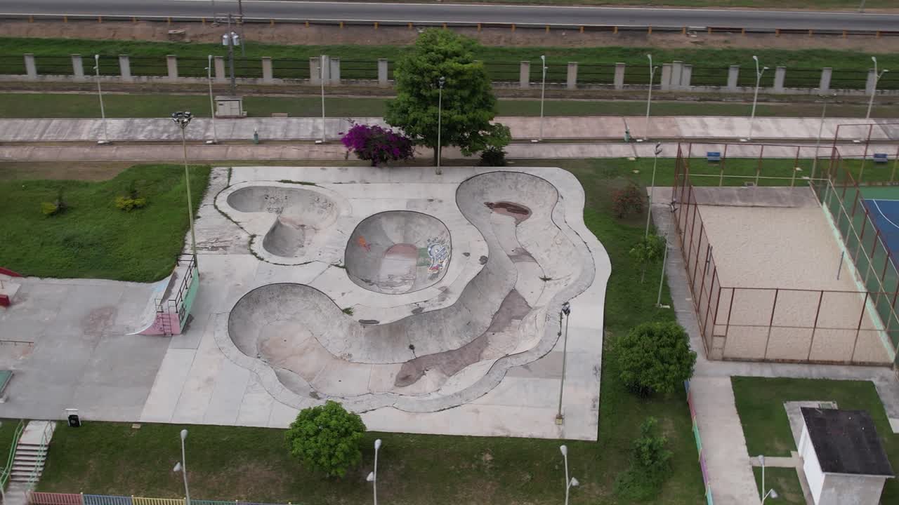 aerial view of La Victoria's Paseo Bicentenario, highlighting the juxtaposition of a large, modern skatepark and brightly colored sports courts against the essential city highway