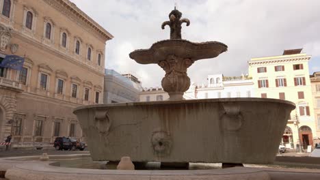 Walking-around-a-decorative-fountain-located-in-the-Piazza-Farnese,-in-front-of-the-Palazzo-Farnese-in-Rome,-Italy