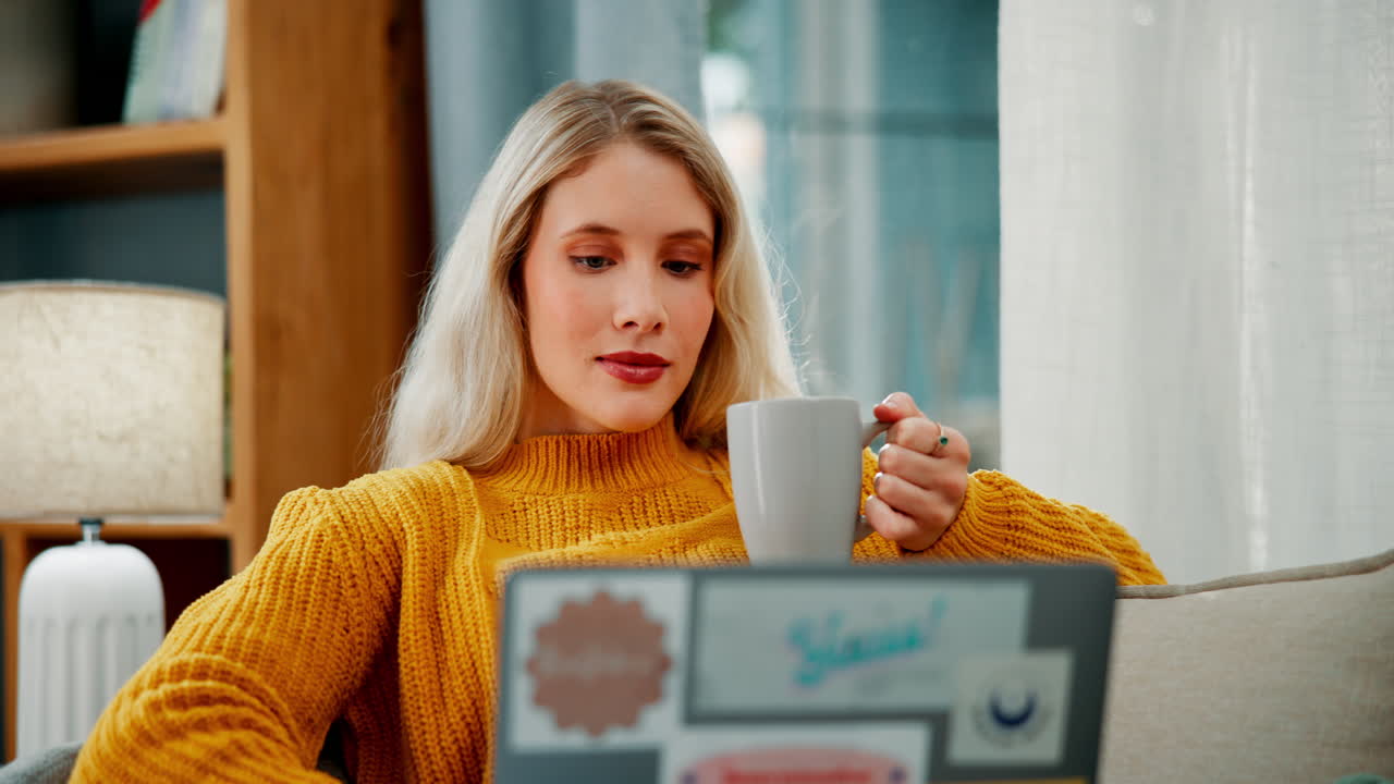 Woman enjoying coffee while working on laptop at home