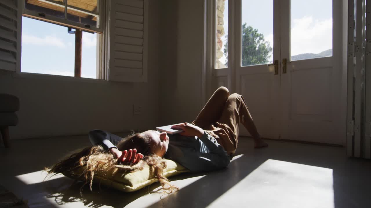 바닥에 누워 있는 백인 여성이 책을 들고  ⁇ 은 오두막 거실에서 자고 있습니다.